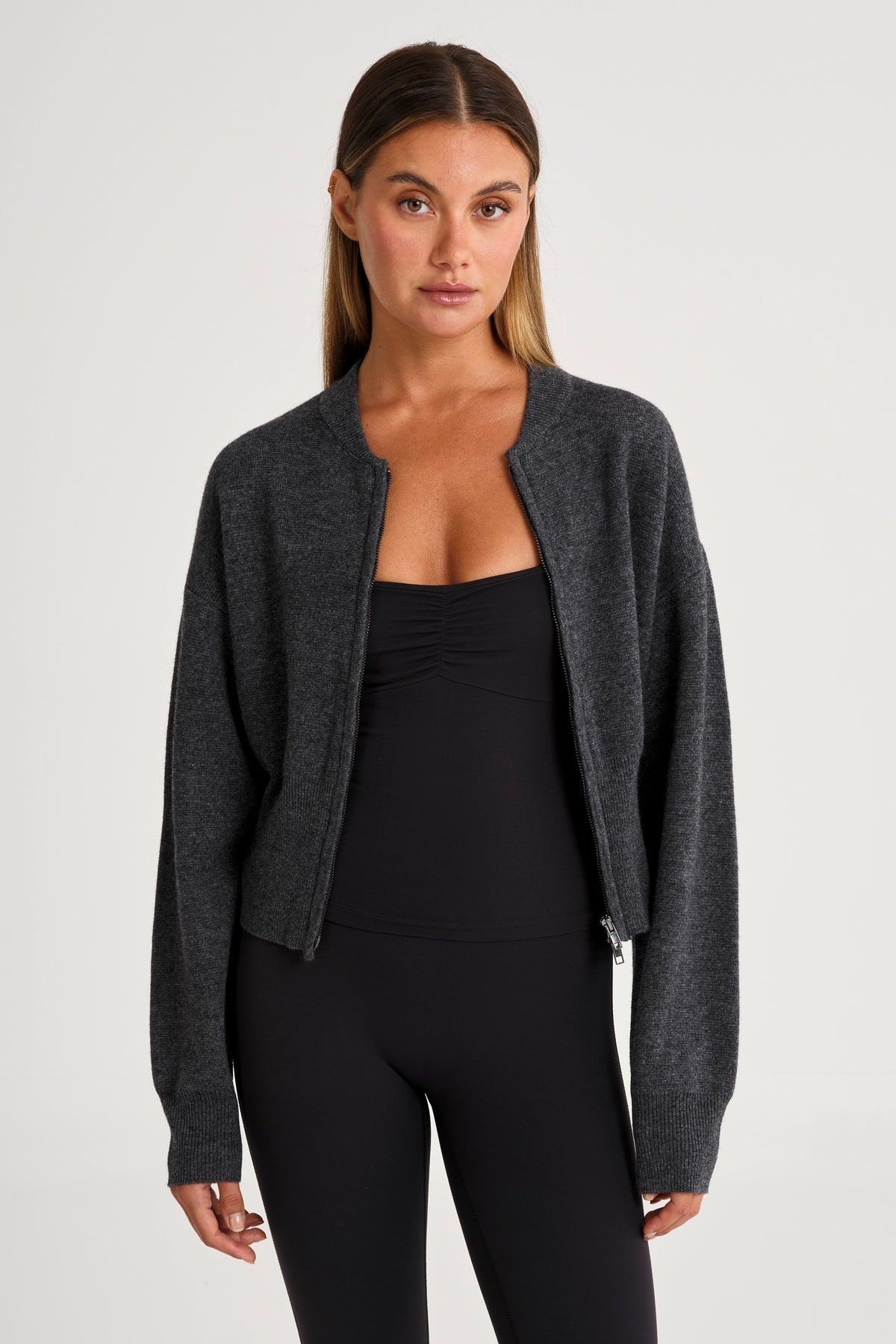 Woman wearing a dark gray cardigan over a black top and leggings