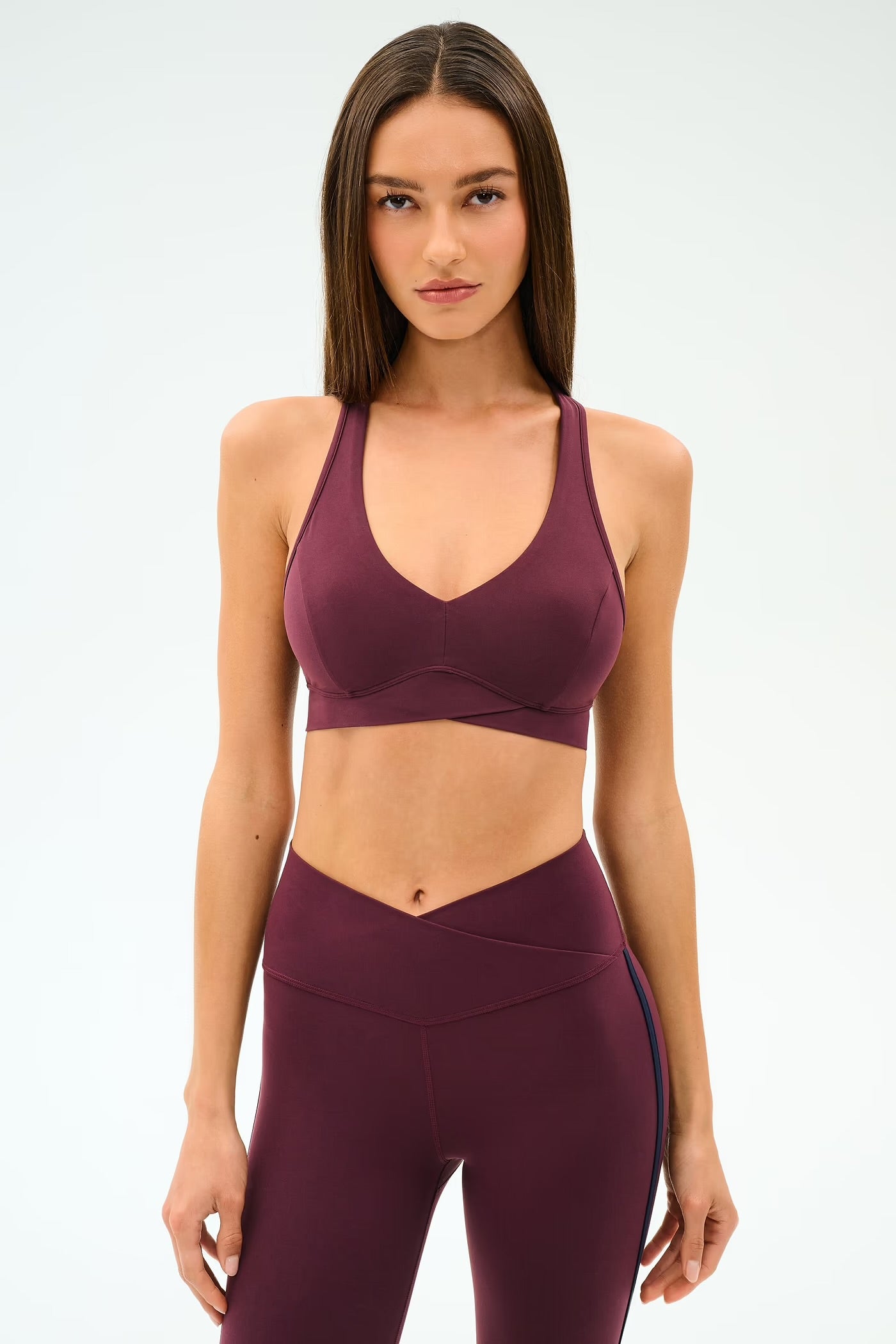 Woman wearing a maroon sports bra and leggings 