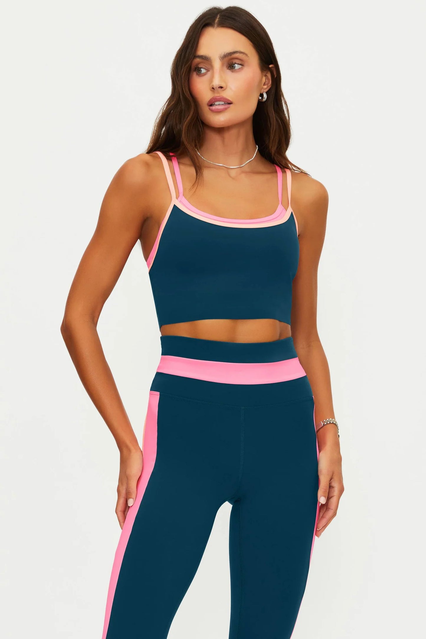 Woman wearing a navy sports bra and leggings with pink accents