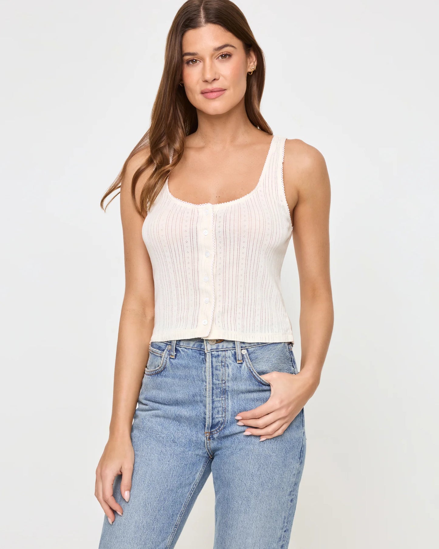 Woman wearing a white ribbed tank top and blue jeans