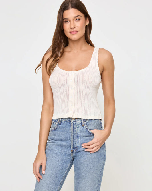 Woman wearing a white ribbed tank top and blue jeans
