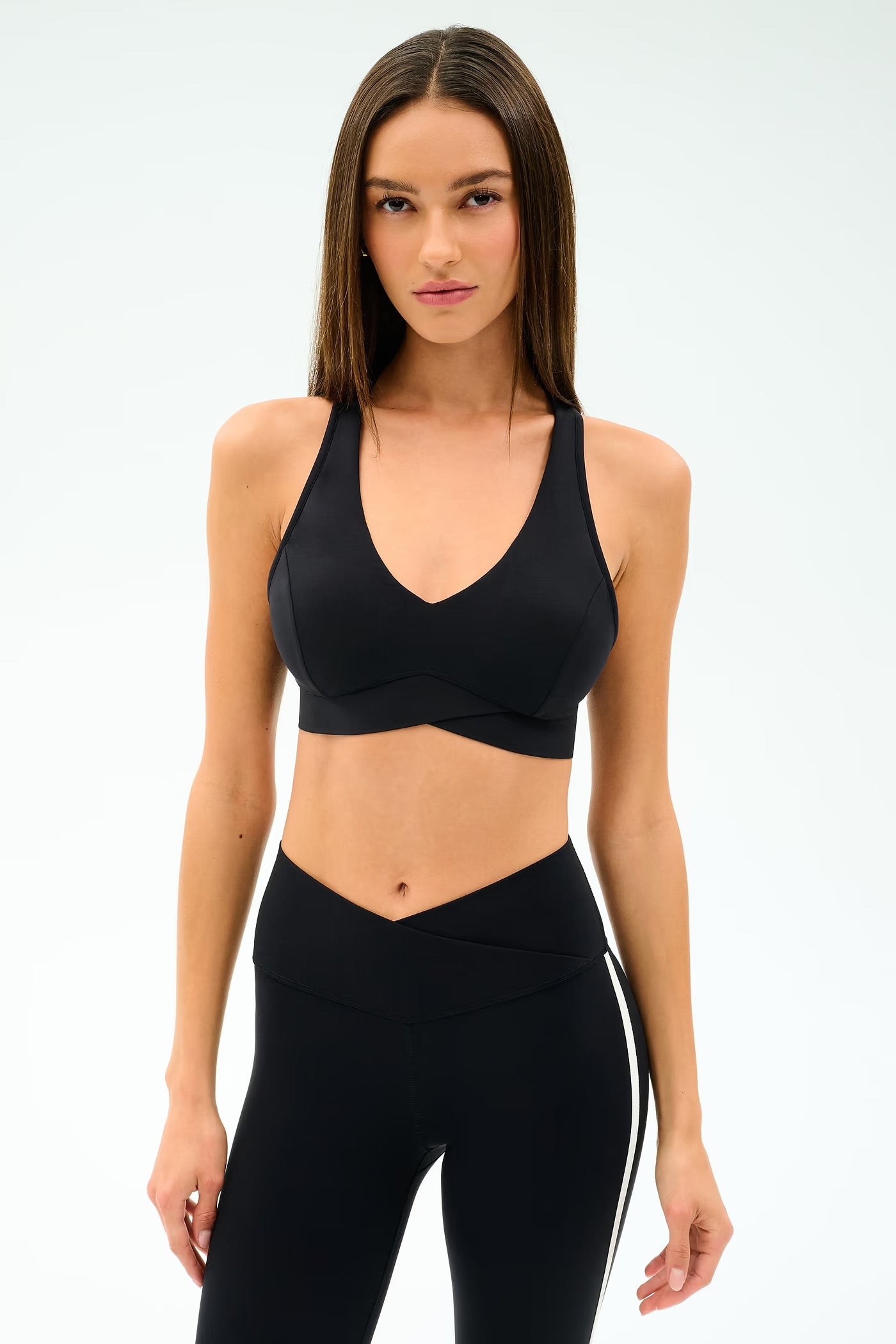 Woman wearing a black sports bra and leggings with a white stripe 