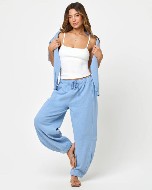 Woman wearing light blue pants and a white top with a light blue sweatshirt