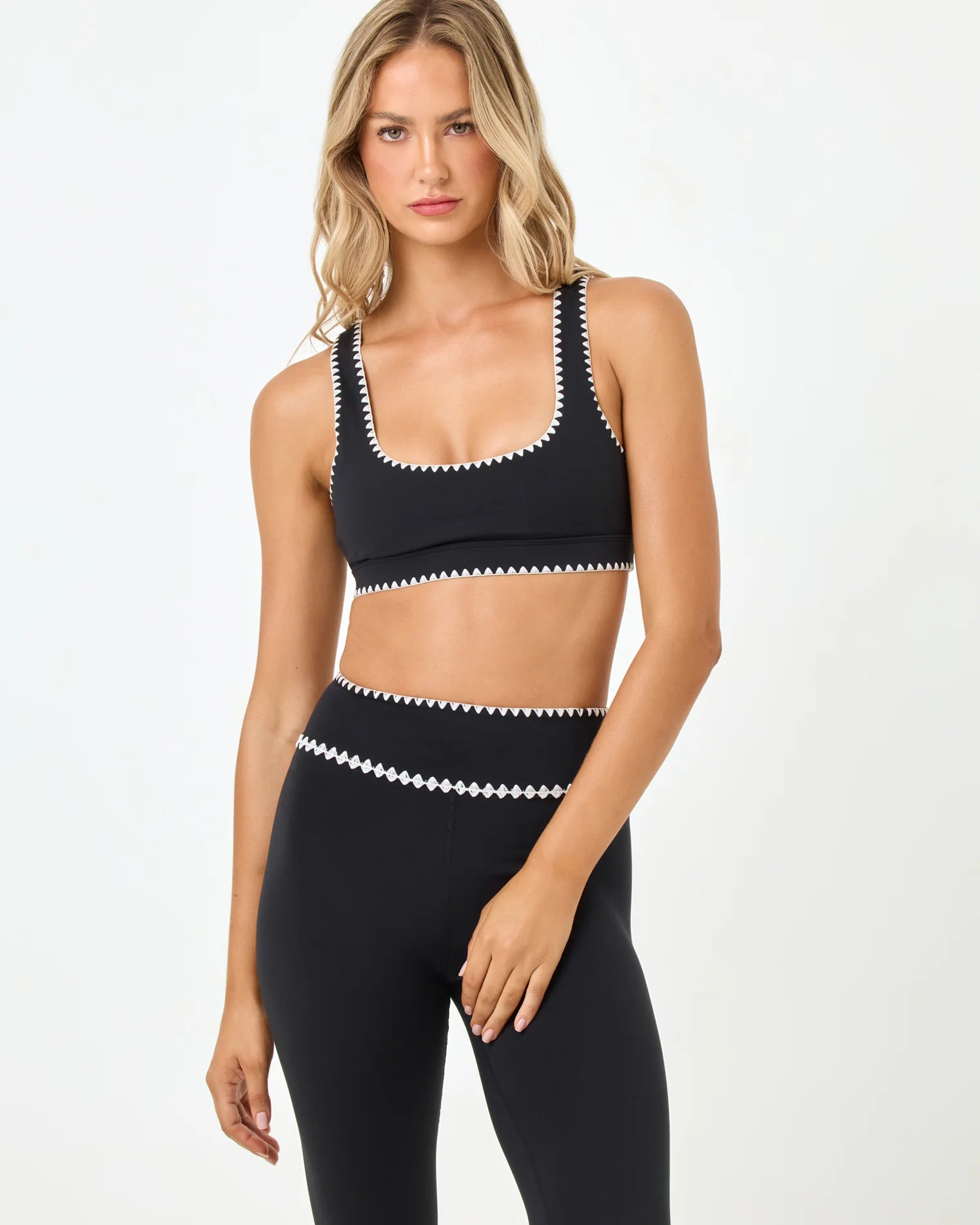 Woman wearing a black sports bra and leggings with white accents