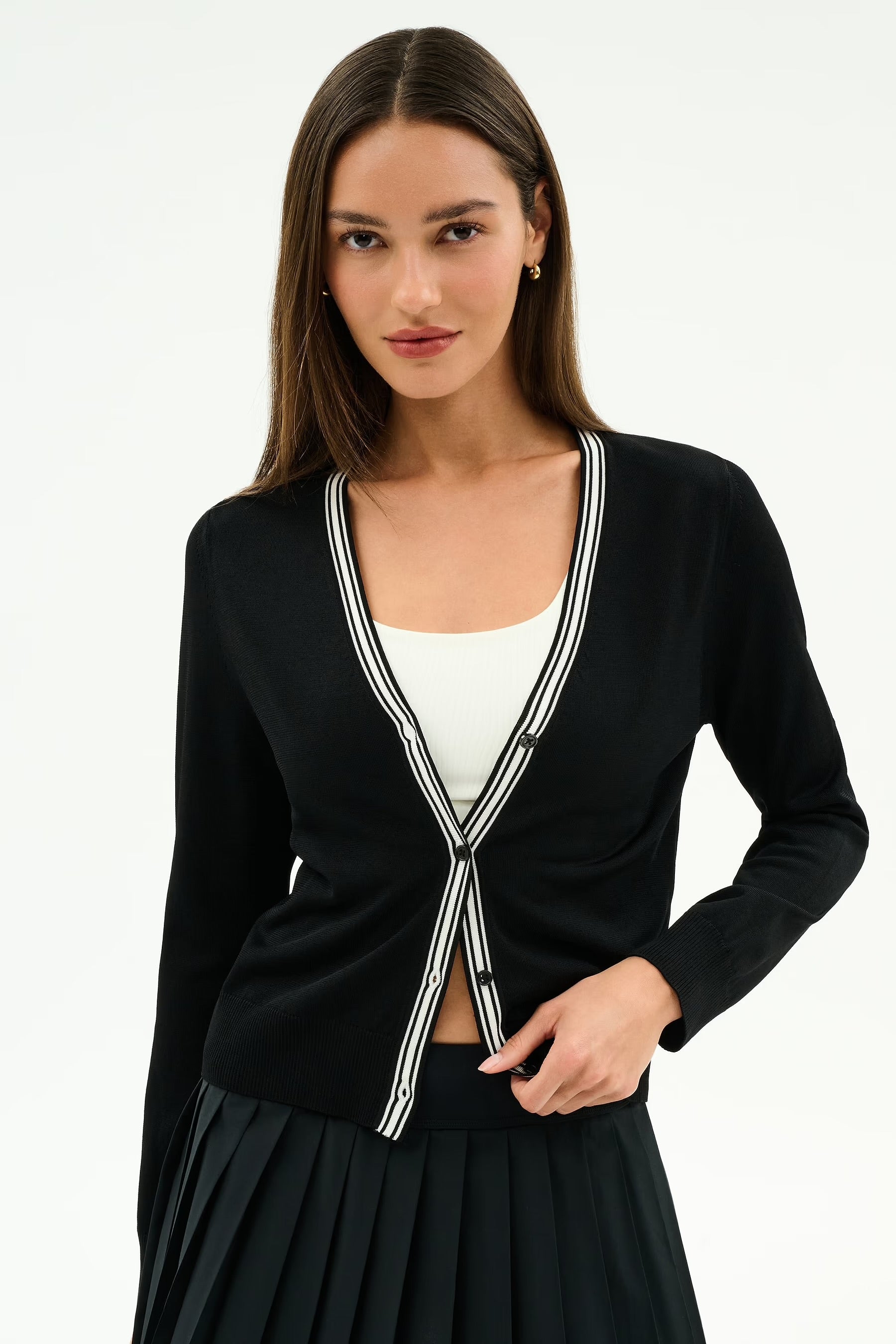 Woman wearing a black cardigan with a white top and black skirt 