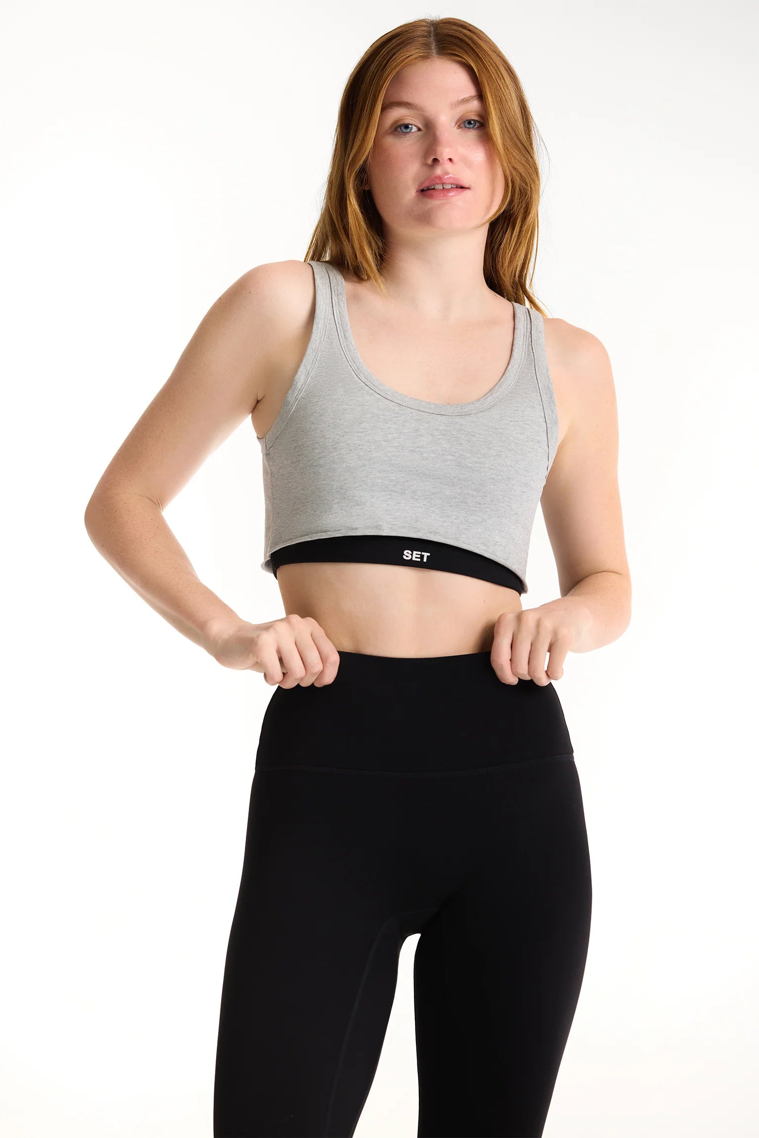 Woman wearing a gray sports bra and black leggings 