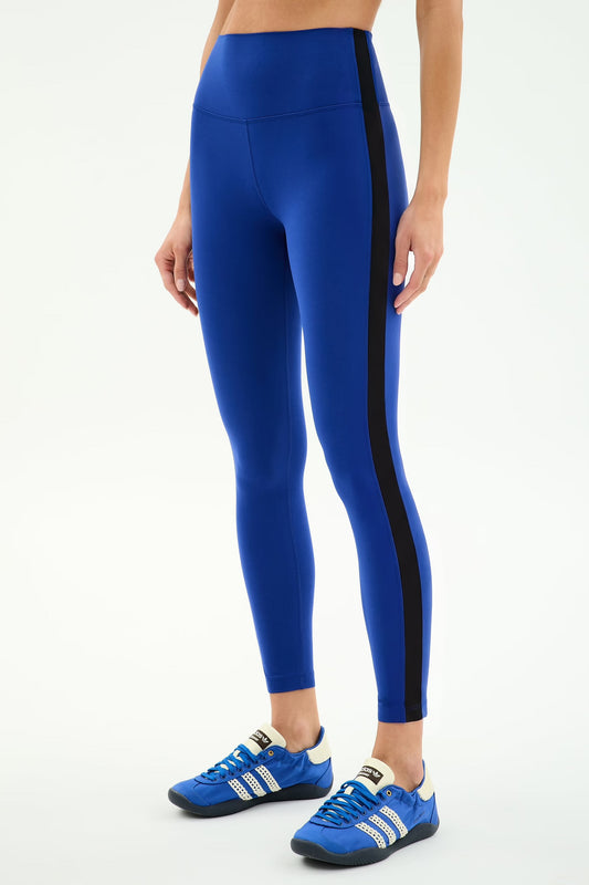 Blue leggings with a black side stripe worn by a person on a white background