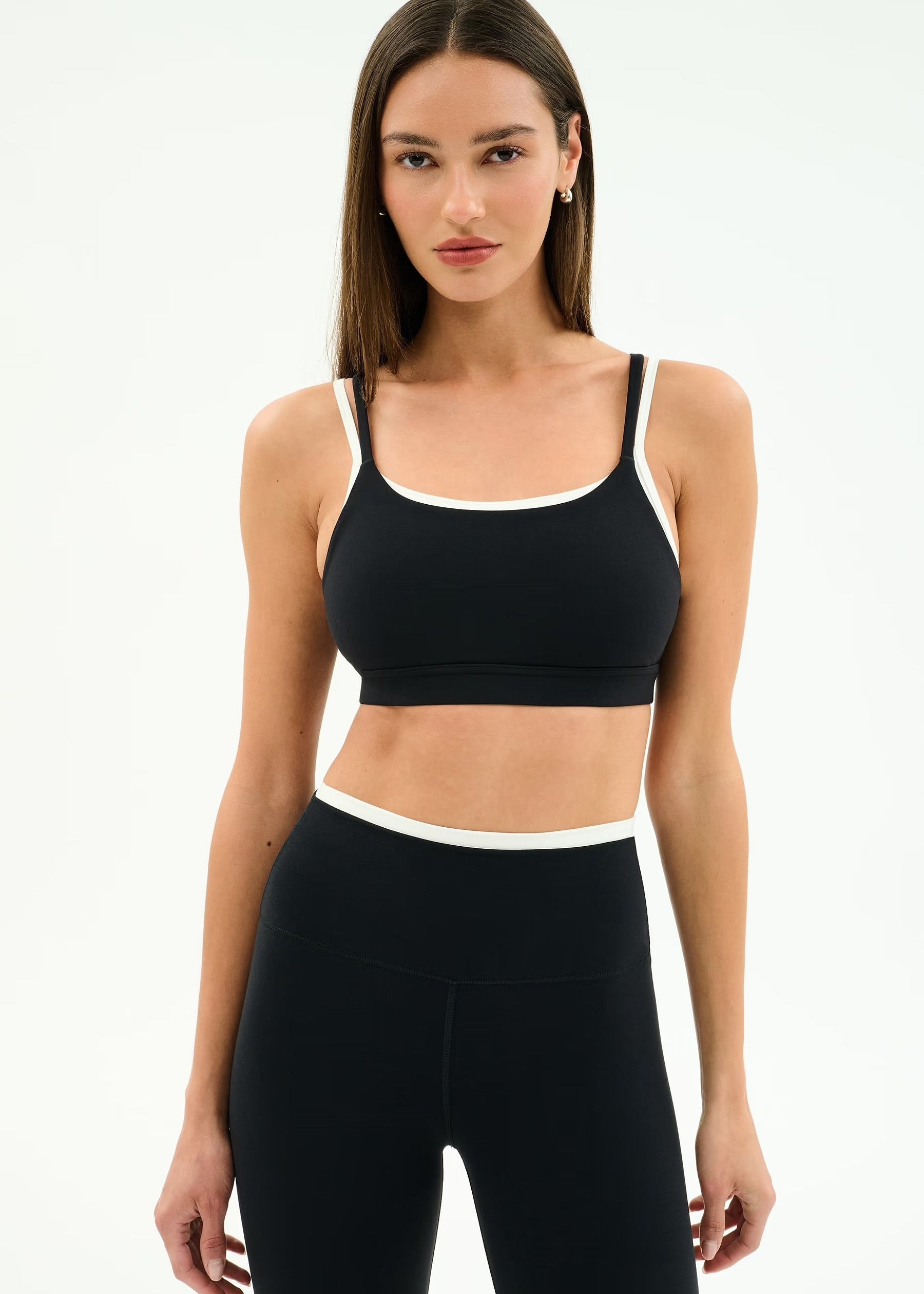 Woman wearing a black sports bra and leggings on a white background