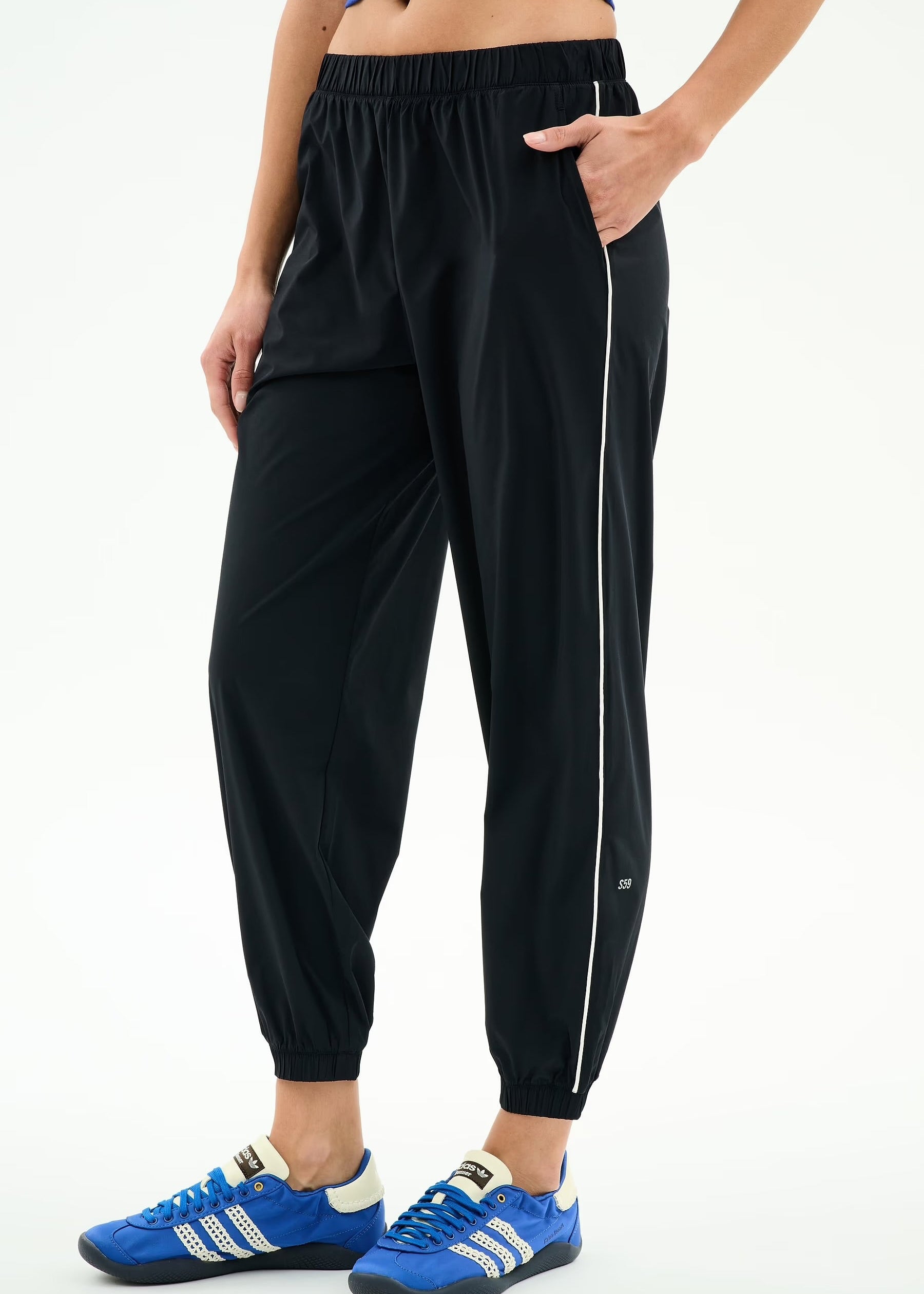 Person wearing black jogger pants with a white stripe on a white background