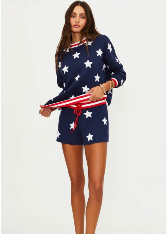 Woman wearing a navy blue outfit with white star patterns, holding an American flag.