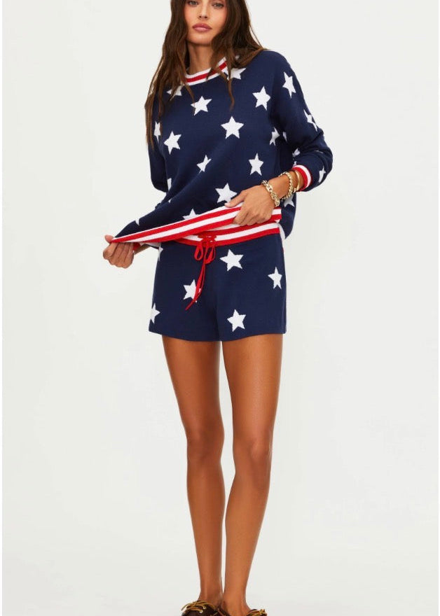Woman wearing a navy blue outfit with white star patterns, holding an American flag.