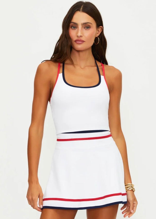 Woman wearing a white tennis dress with red and blue accents on a white background