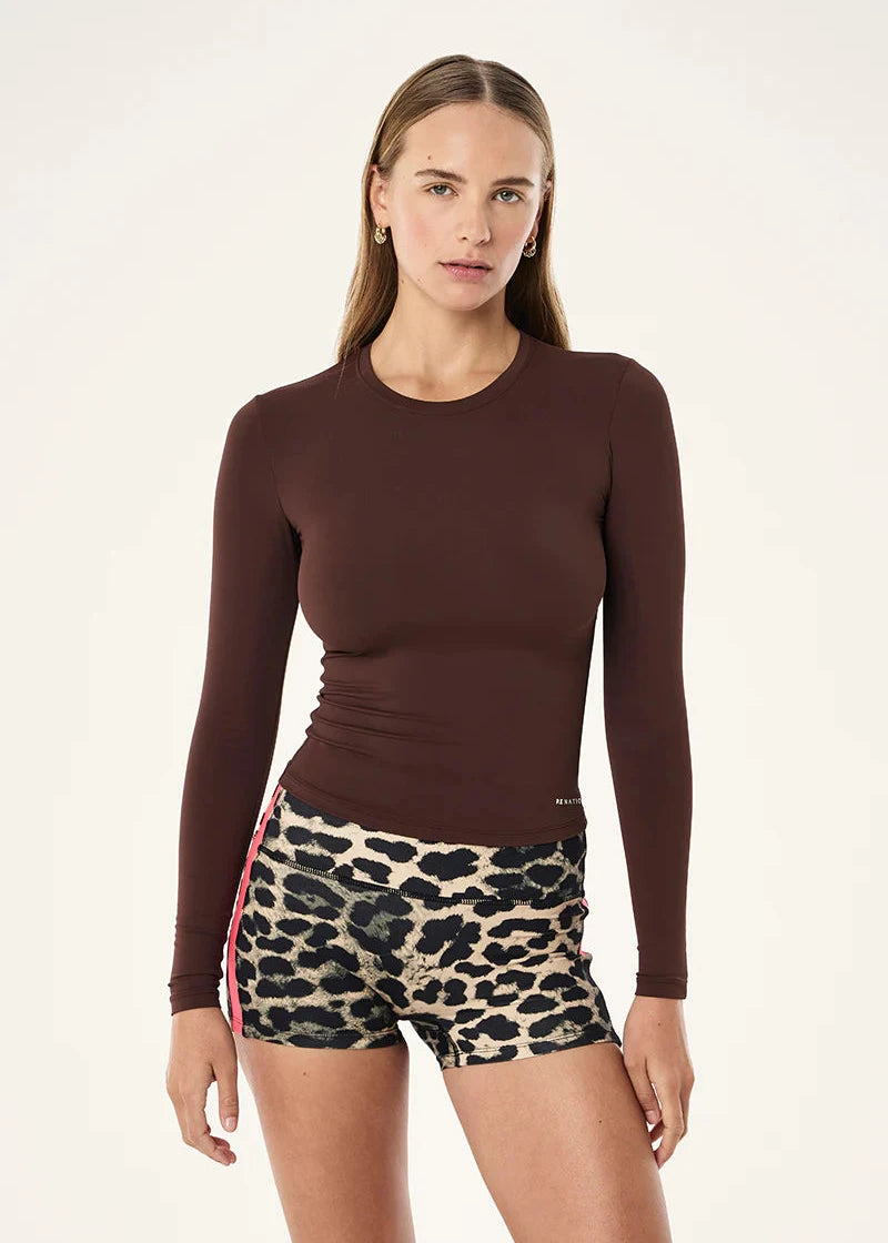 Woman wearing a brown long-sleeve top and leopard print shorts on a white background