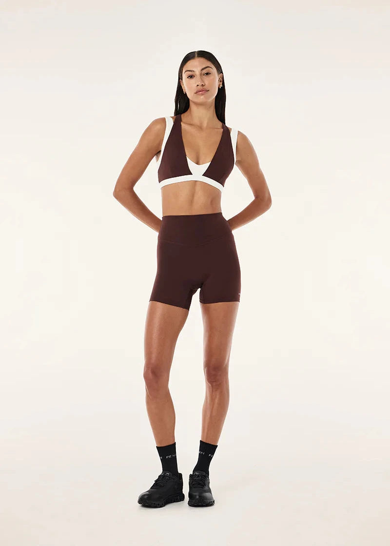 Woman wearing a brown sports bra and shorts set on a white background